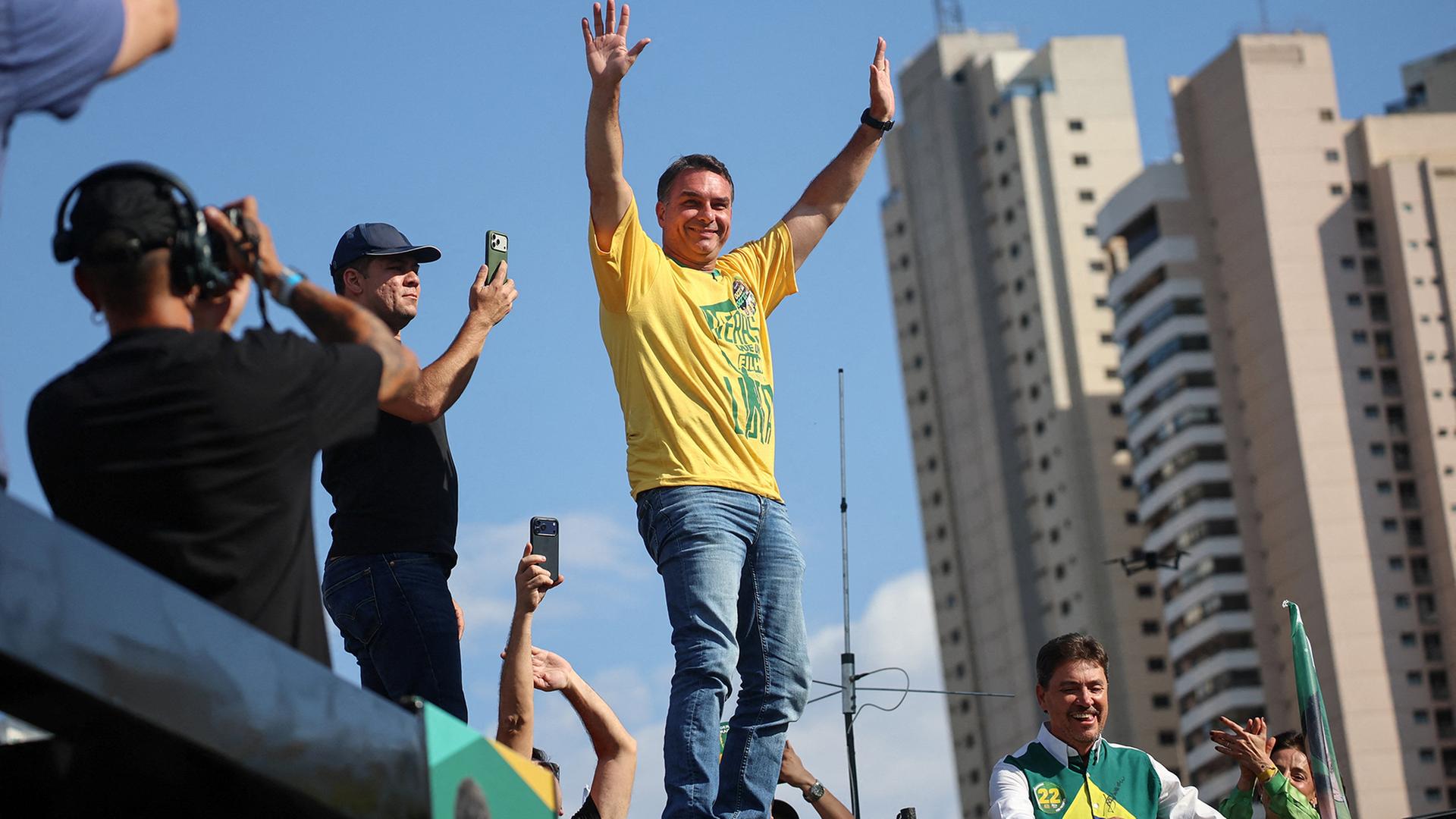 Flávio Bolsonaro steht erfreut auf einem Podest. | REUTERS