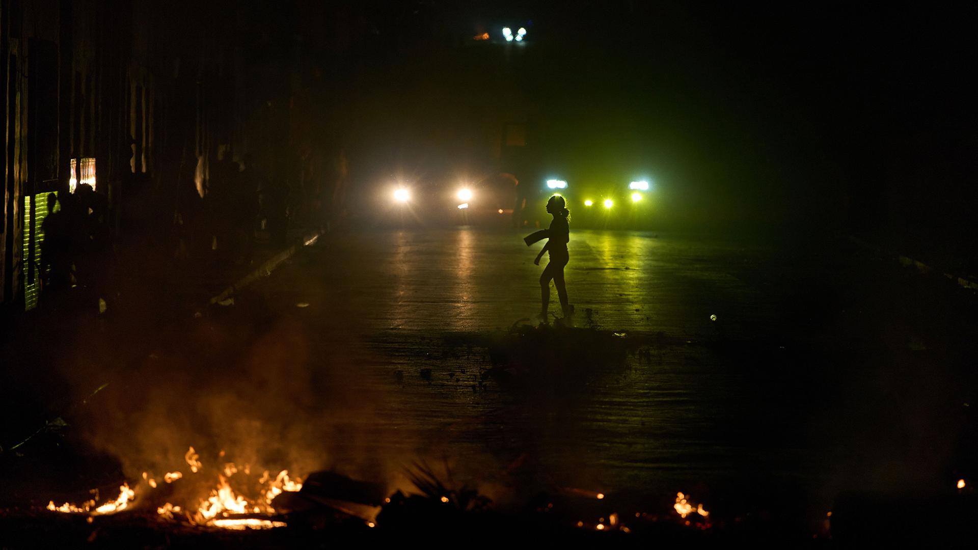 Eine Frau geht an einer Barrikade vorbei, die von Anwohnern errichtet wurde in Havanna, Kuba. | Ramon Espinosa/AP/dpa