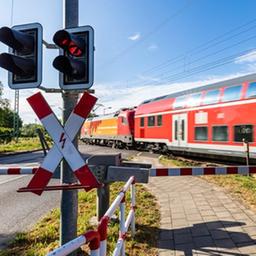 Eine Schranke ist an einem Bahnübergang in Lübbenau geschlossen, wärend ein Zug vorbeifährt.