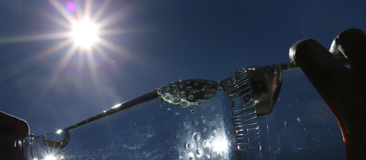 Eine Frau trinkt im Sonnenschein aus einer Flasche Mineralwasser