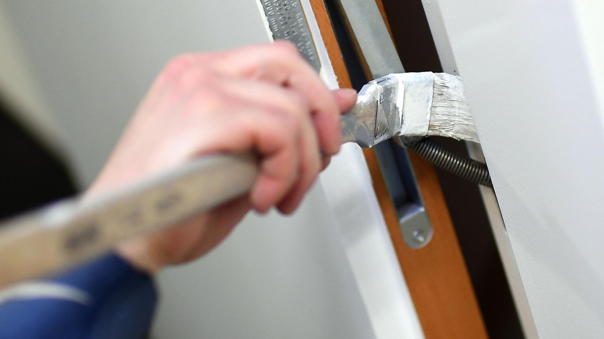 Ein Mann streicht eine Türzarge mit weißer Farbe. | picture alliance/dpa/dpa-Zentral