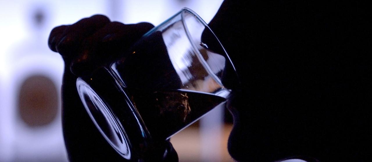 Ein Bar-Besucher genießt in einer Bar ein Glas Whiskey mit Eis.