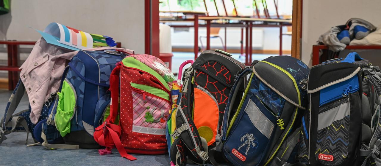 Schulranzen stehen vor einem Klassenraum einer Grundschule.