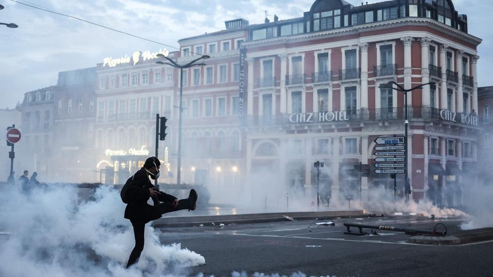 Ein Demonstrant mit Gasmaske tritt eine Tränengaskartusche auf einer Kreuzung in Toulouse weg.
