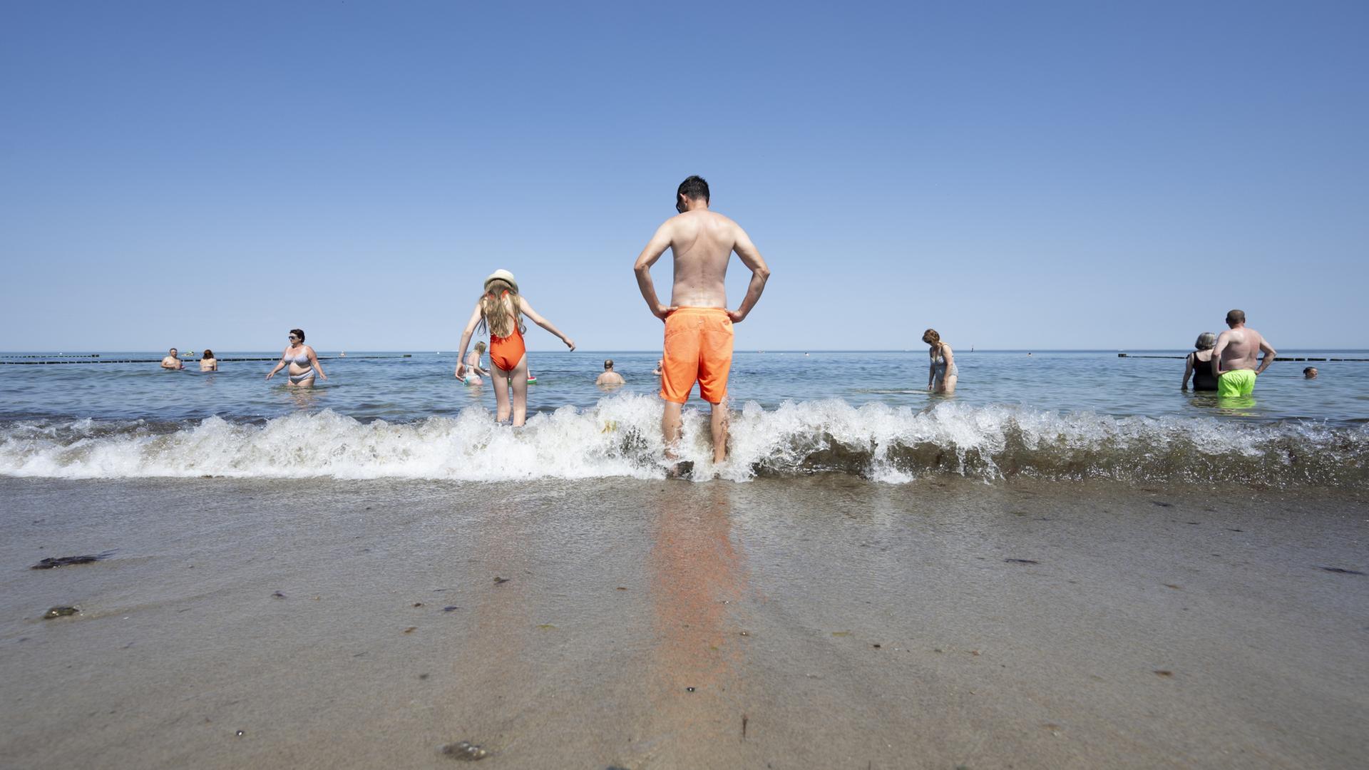 Menschen stehen im Wasser am Ostseestrand in Kühlungsborn.