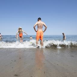 Menschen stehen im Wasser am Ostseestrand in Kühlungsborn.