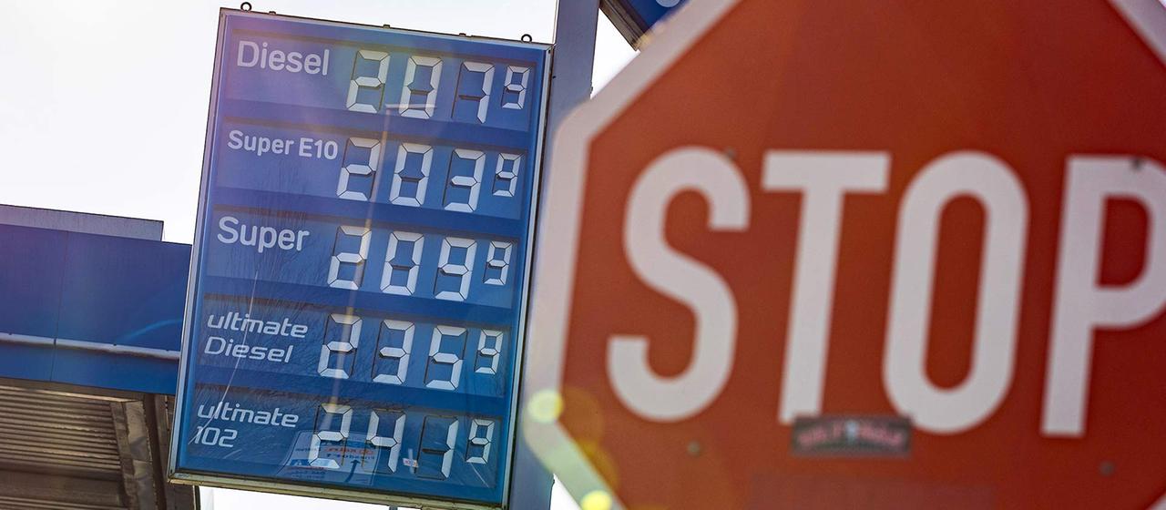 Ein Stop-Schild neben der Preisanzeige einer Tankstelle.