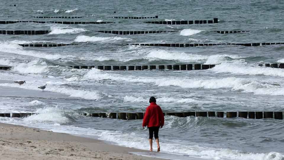 Eine Spaziergängerin ist am Ostseestrand unterwegs. 