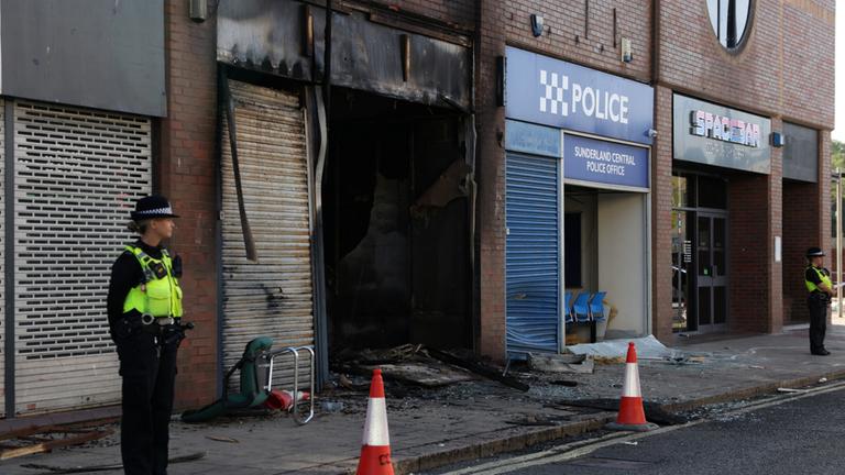 In Sunderland steht eine Polizeibeamtin neben einem in Brand gesetzten Gebäude. 