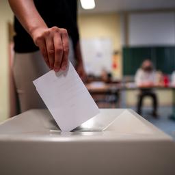 Eine Frau wirft einen Wahlzettel in eine Wahlurne