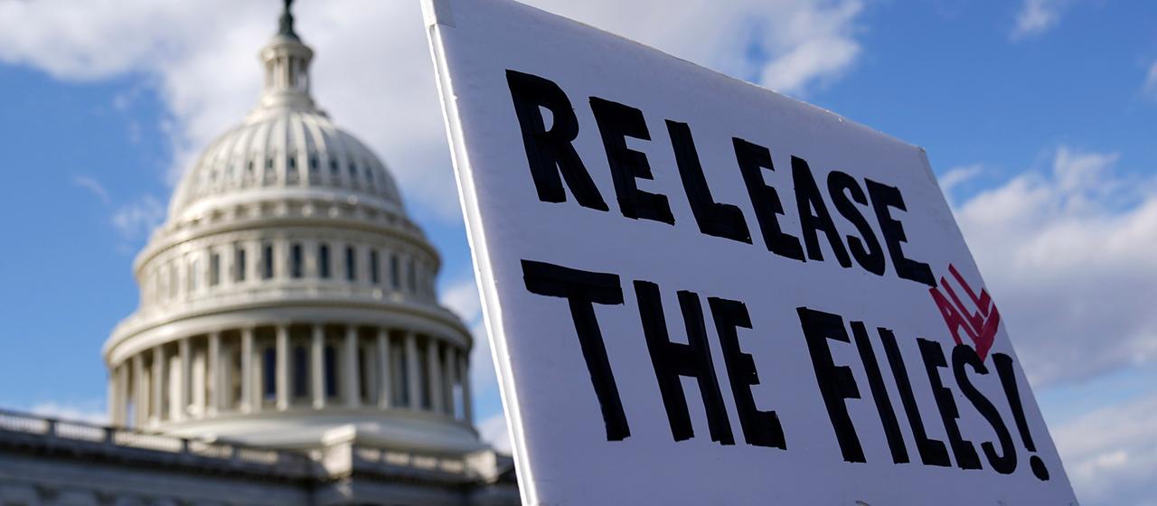 Ein Demonstrant hält ein Schild mit der Aufschrift "RELEASE ALL THE FILES!", im Hintergrund das Capitol in Washington, D.C.