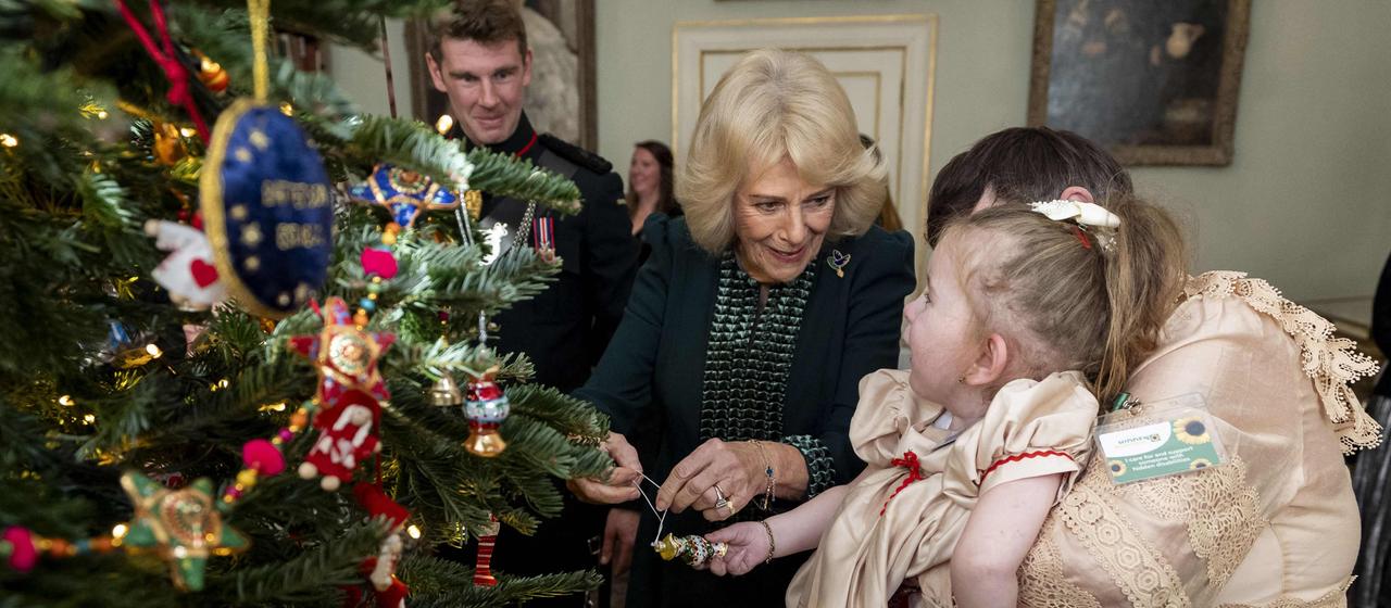 Königin Camilla und Kinder schmücken den Weihnachtsbaum.