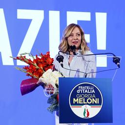 Giorgia Meloni steht mit einem Blumenstrauß an einem Rednerpult.