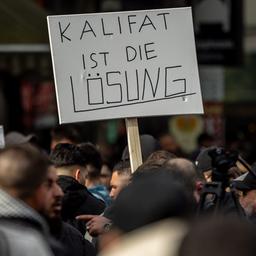 Teilnehmer einer Islamisten-Demonstration in Hamburg halten ein Plakat mit der Aufschrift "Kalifat ist die Lösung" in die Höhe.