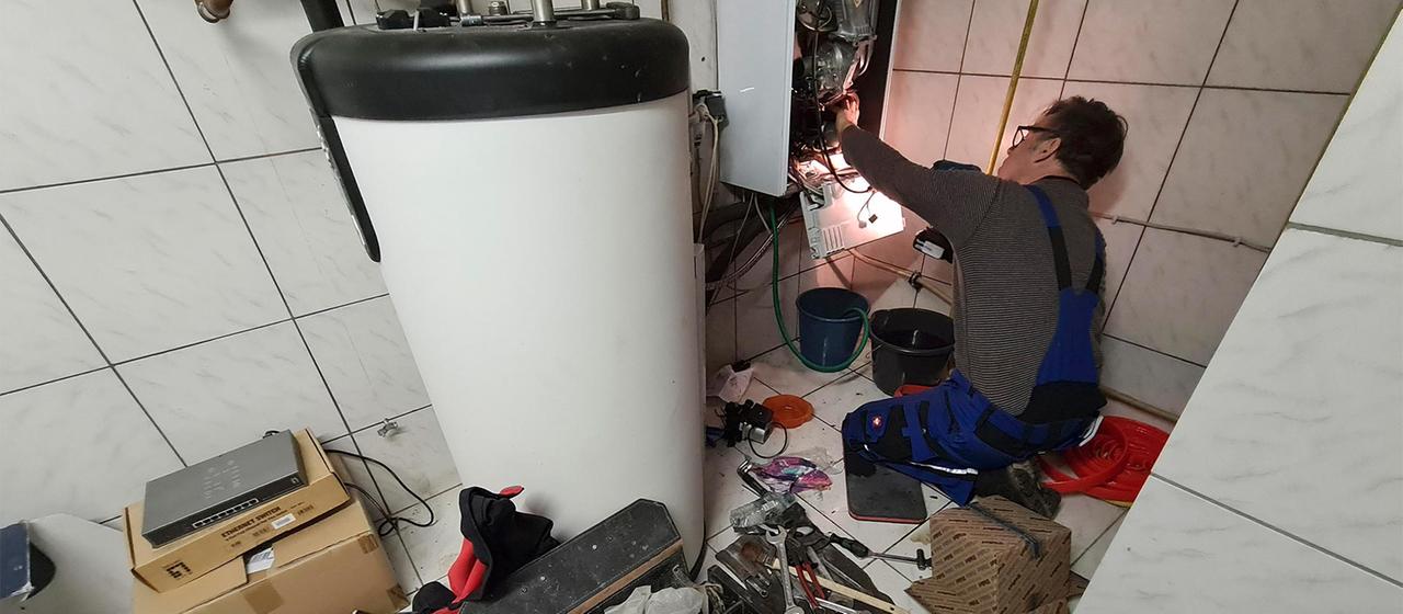 Ein Handwerker bei der Wartung einer Gastherme.