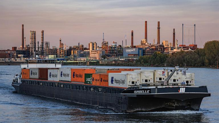 Ein Schiff fährt am Abend an dem Werk des Bayer Konzerns im Chempark vorbei.