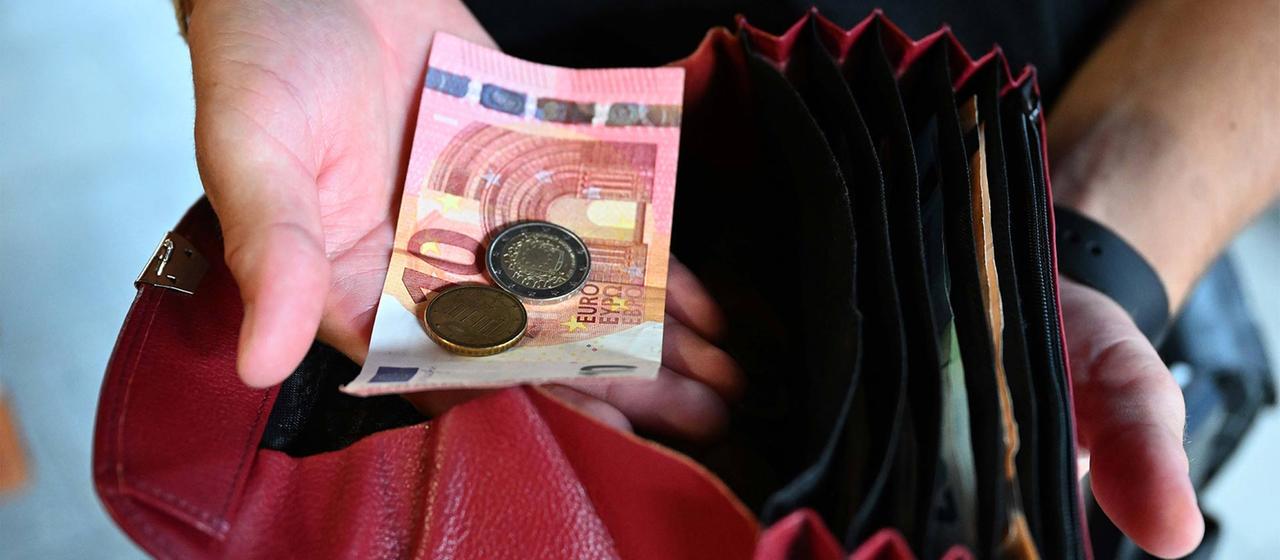 Ein Kellner eines Restaurants hält einen Geldbeutel in der Hand, während er in der anderen Hand Geld hält. 