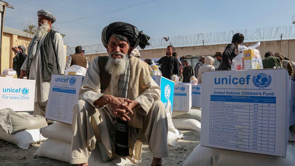 Ein Mann in Kabul (Afghanistan) sitzt neben Hilfsgütern der Vereinten Nationen.