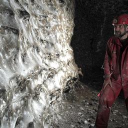 Ein Wissenschaftler in einer Höhle neben einem riesigen Spinnennetz
