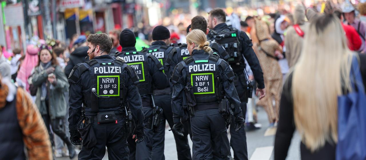 Polizisten patrouillieren während der Karnevalssession durch eine Straße in Köln.
