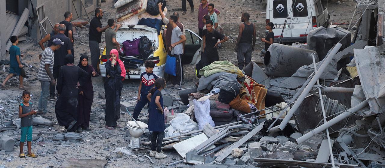 Menschen stehen zwischen Trümmern in Gaza-Stadt.