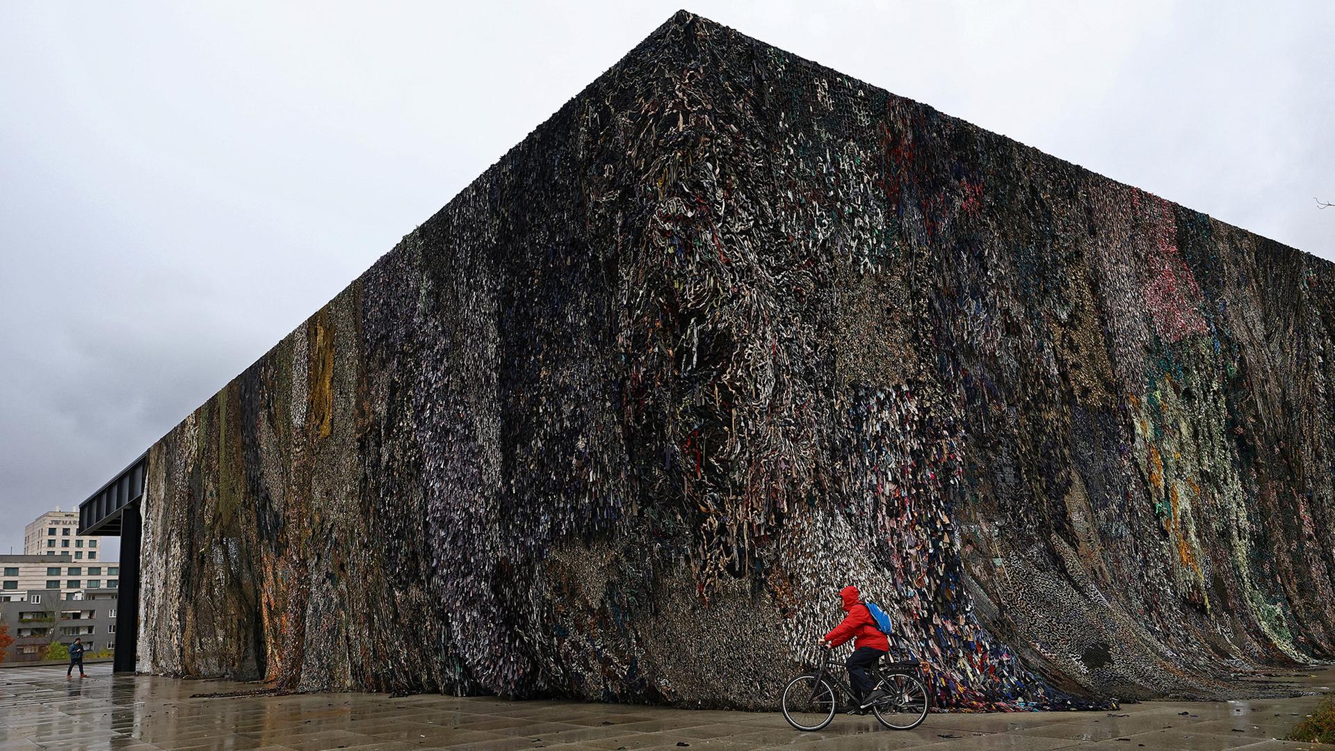 Ein Radfahrer fährt mit seinem Fahrrad an der Neuen Nationalgalerie in Berlin vor dem Kunstwerk