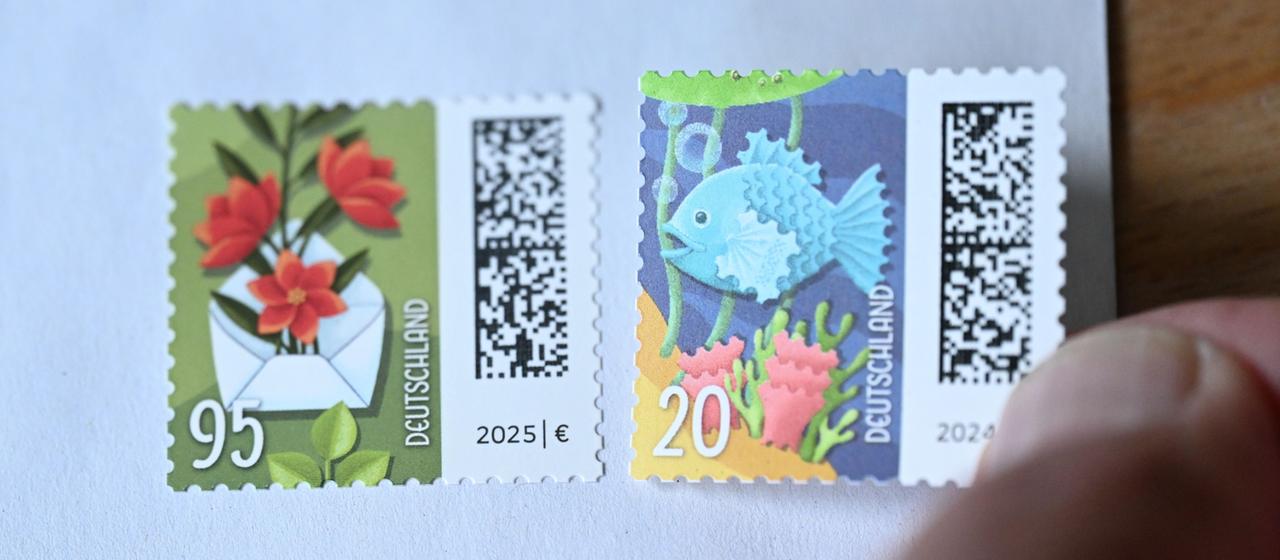 Eine Hand klebt eine 20-Cent-Briefmarke neben eine 95-Cent-Briefmarke.