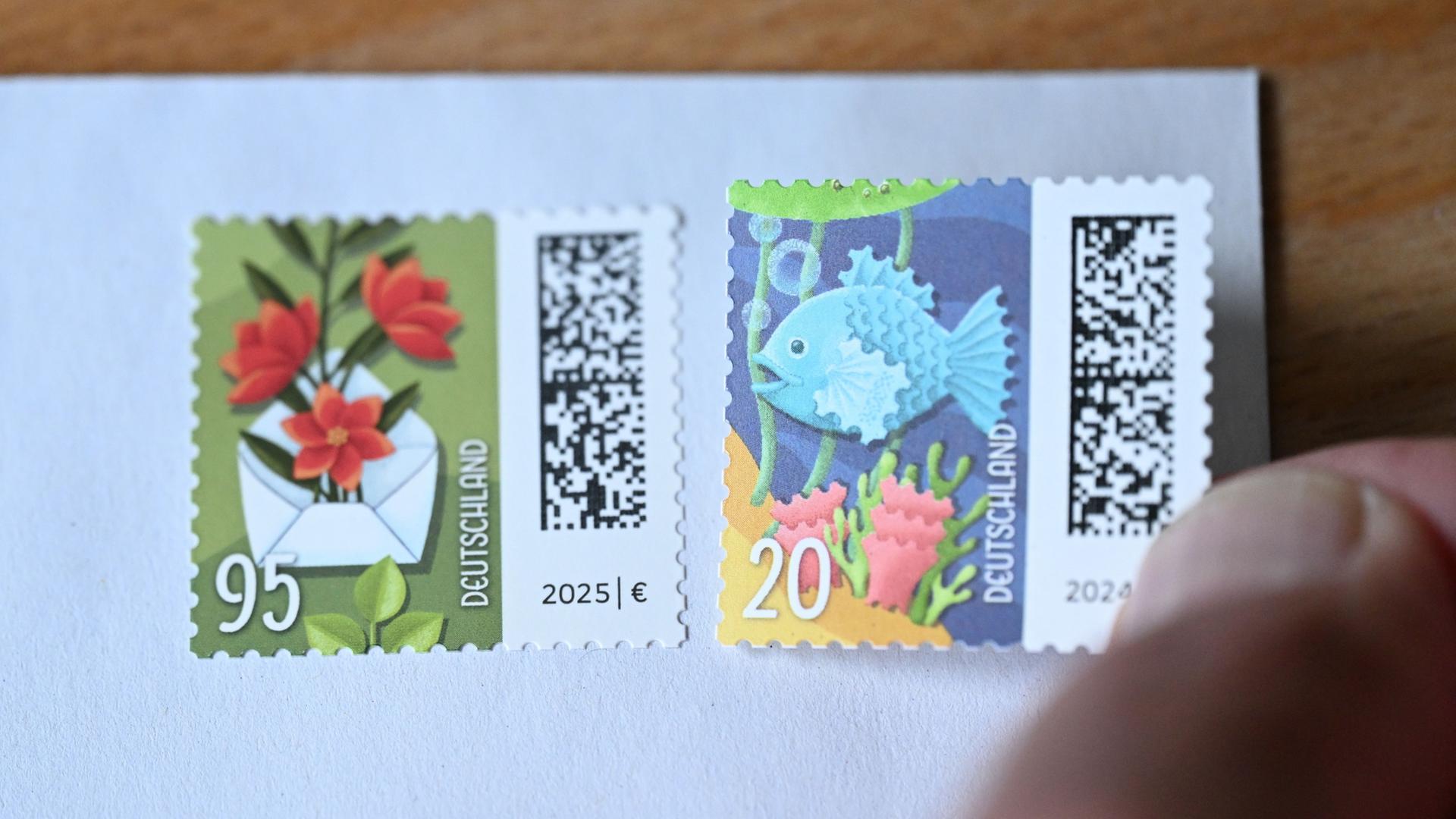 Eine Hand klebt eine 20-Cent-Briefmarke neben eine 95-Cent-Briefmarke. | Bernd Wei�brod/dpa
