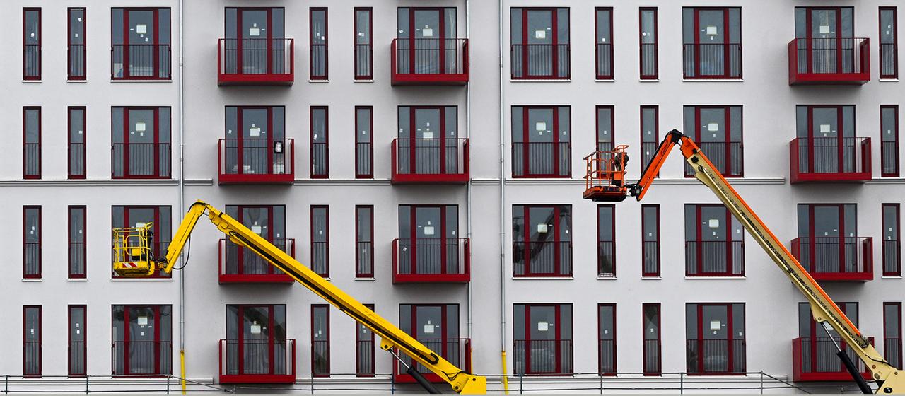 Die Fassade eines im Bau befindlichen Mehrfamilienhauses mit Hubarbeitsbühnen.