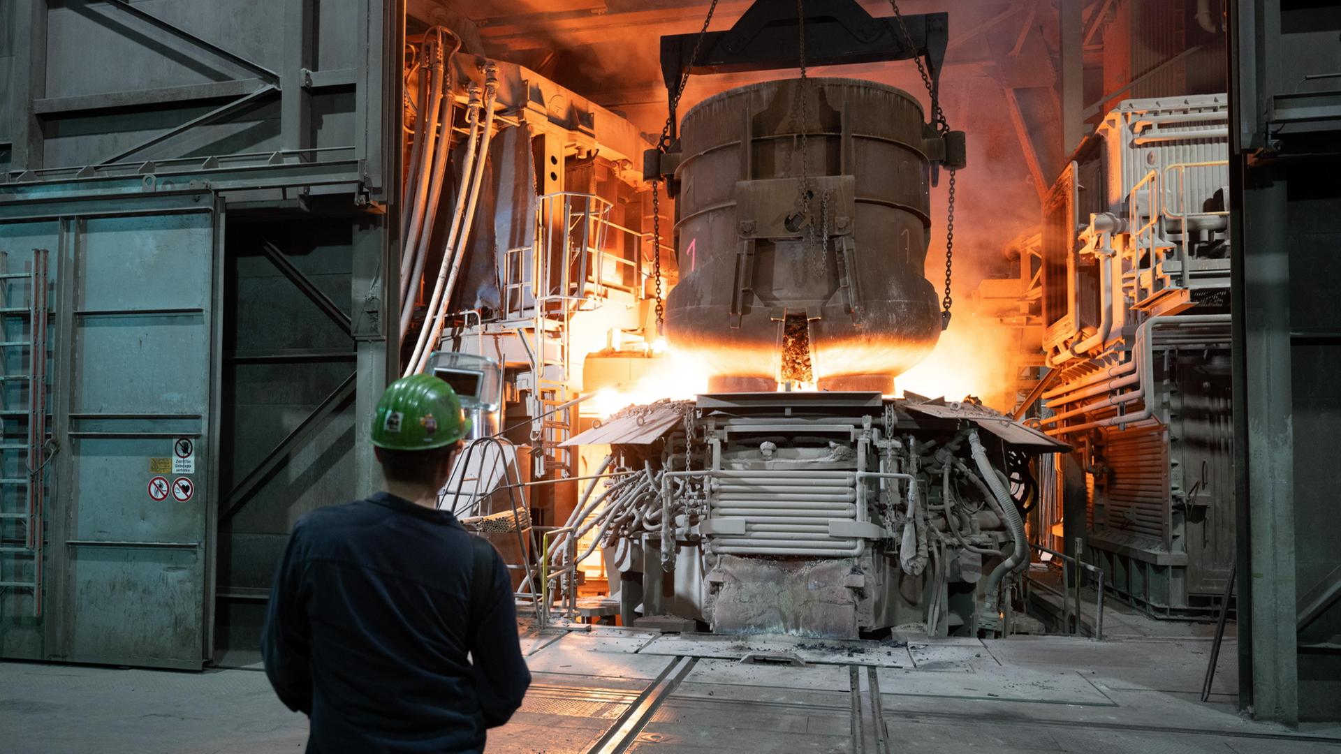 Ein Mitarbeiter steht in einer Werkhalle der BGH Edelstahl Freital GmbH an einem Lichtbogenofen. | dpa
