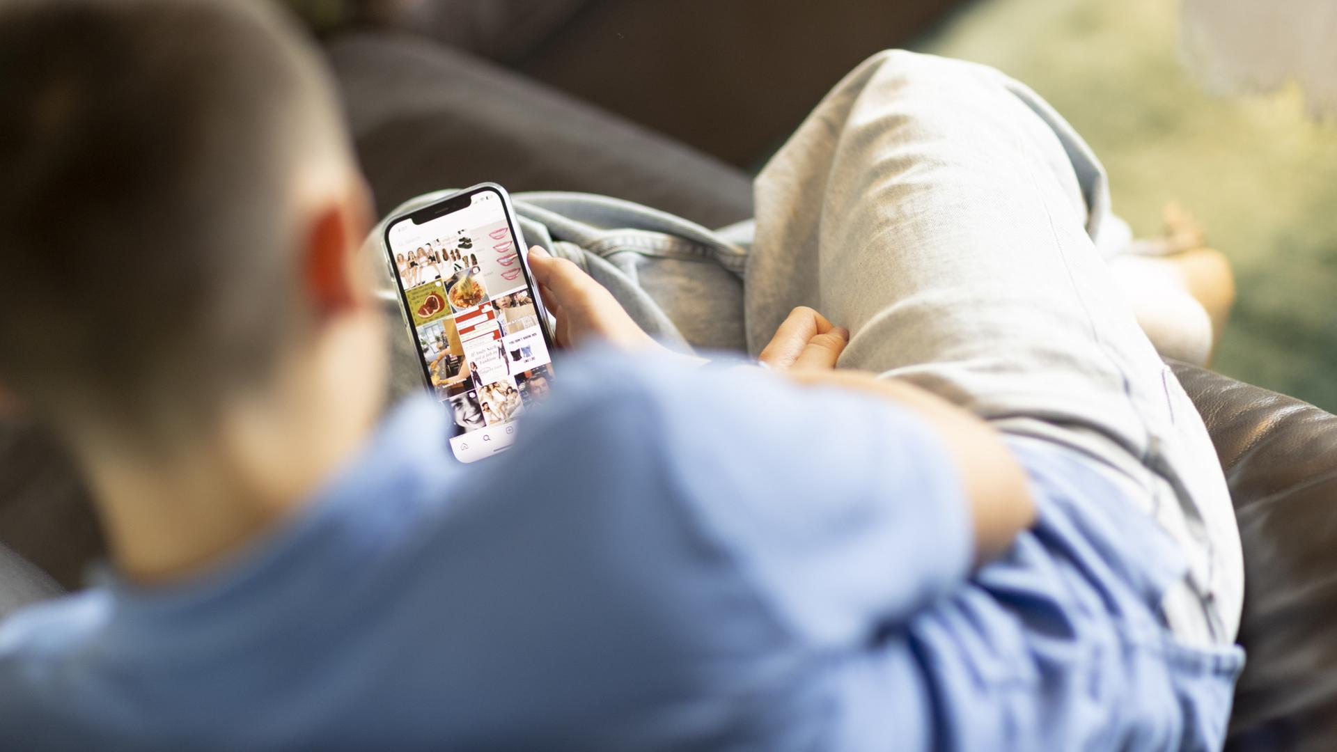 Ein Kind sitzt auf einem Sofa und schaut auf ein Handy. | ARD-aktuell / Andreas Weiss