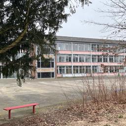 Bild von der Gesamtschule Nordstadt in Neuss mit einer roten Bank vor der Schule