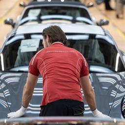 Ein Mitarbeiter der Porsche AG steht in einem Lichttunnel in der Produktion im Stammwerk in Zuffenhausen zwischen Porsche 911 Sportwagen.