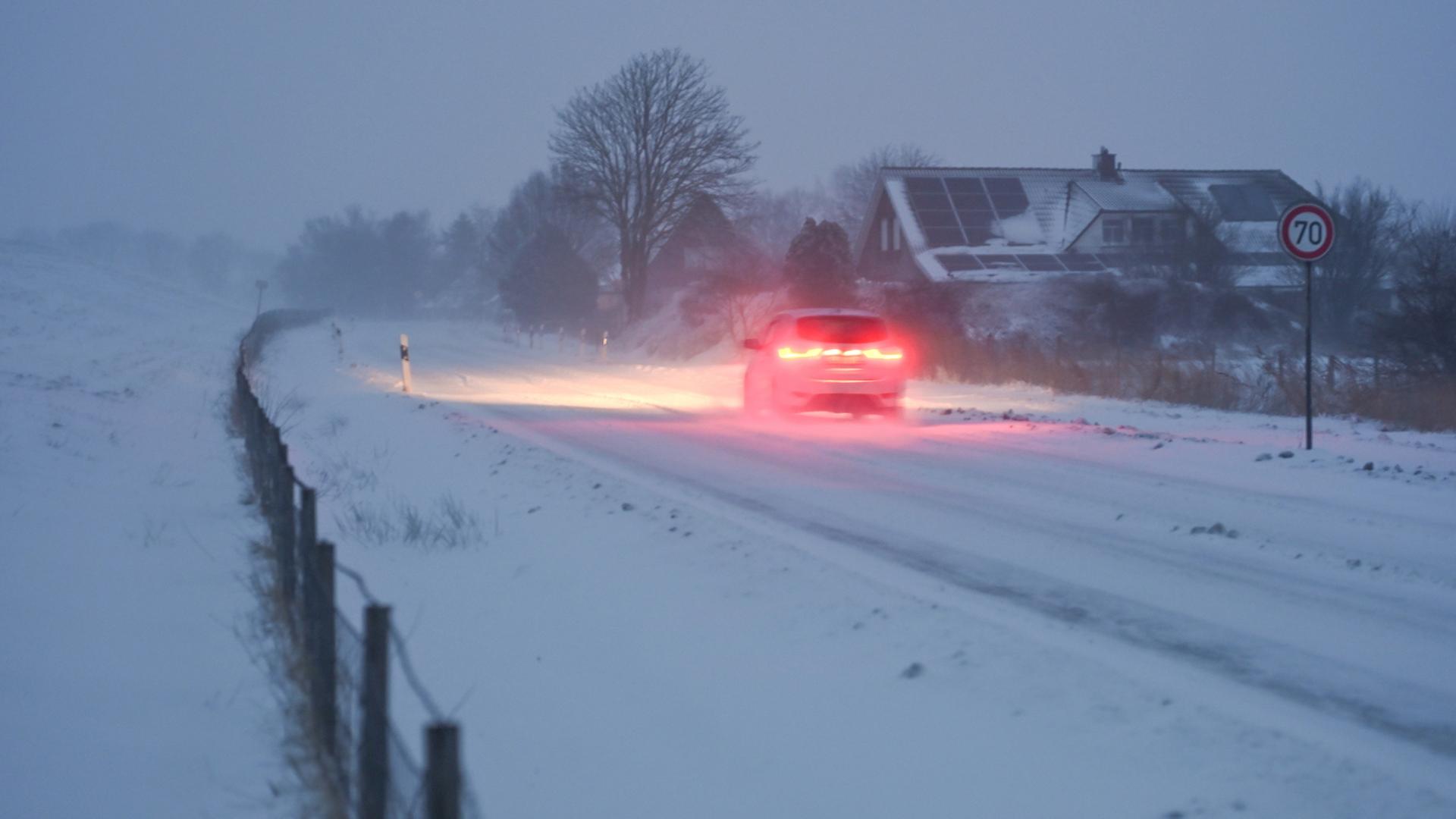 Ein Auto fährt in Moormerland eine verschneite Straße entlang. | dpa