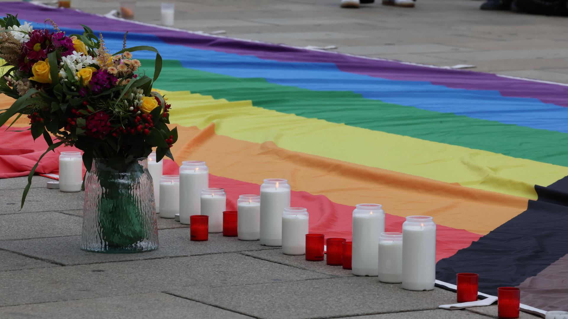 Blumen, Kerzen und eine Regenbogenfahne liegen bei einer Mahnwache für die Opfer einer Attacke beim Berliner CSD auf dem Bahnhofsvorplatz in Erfurt | Bodo Schackow/dpa