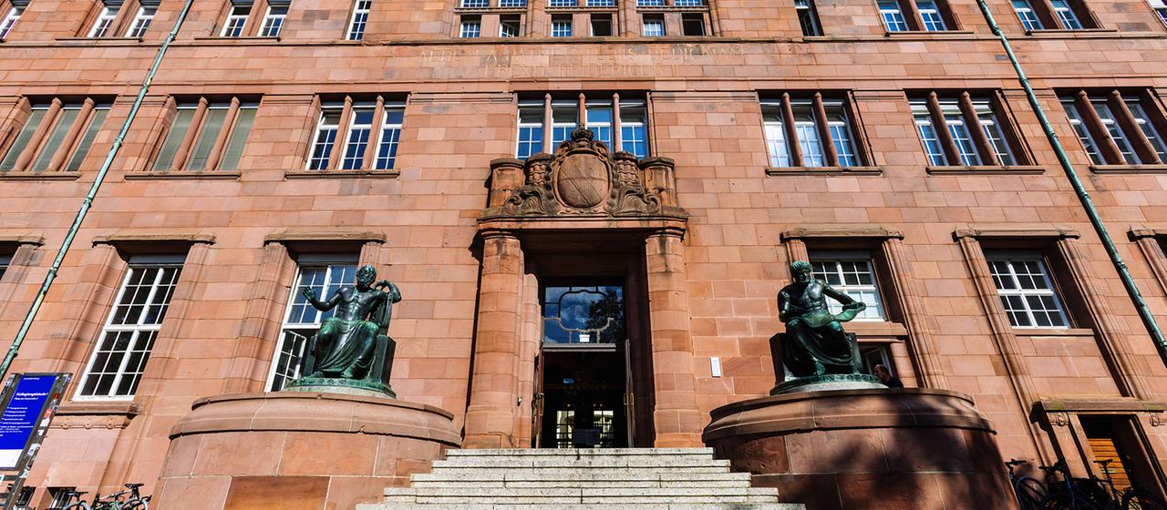 Skulpturen von Homer (l) und Aristoteles rahmen den Haupteingang des Kollegiengebäude I (KG1) der Universität Freiburg ein.