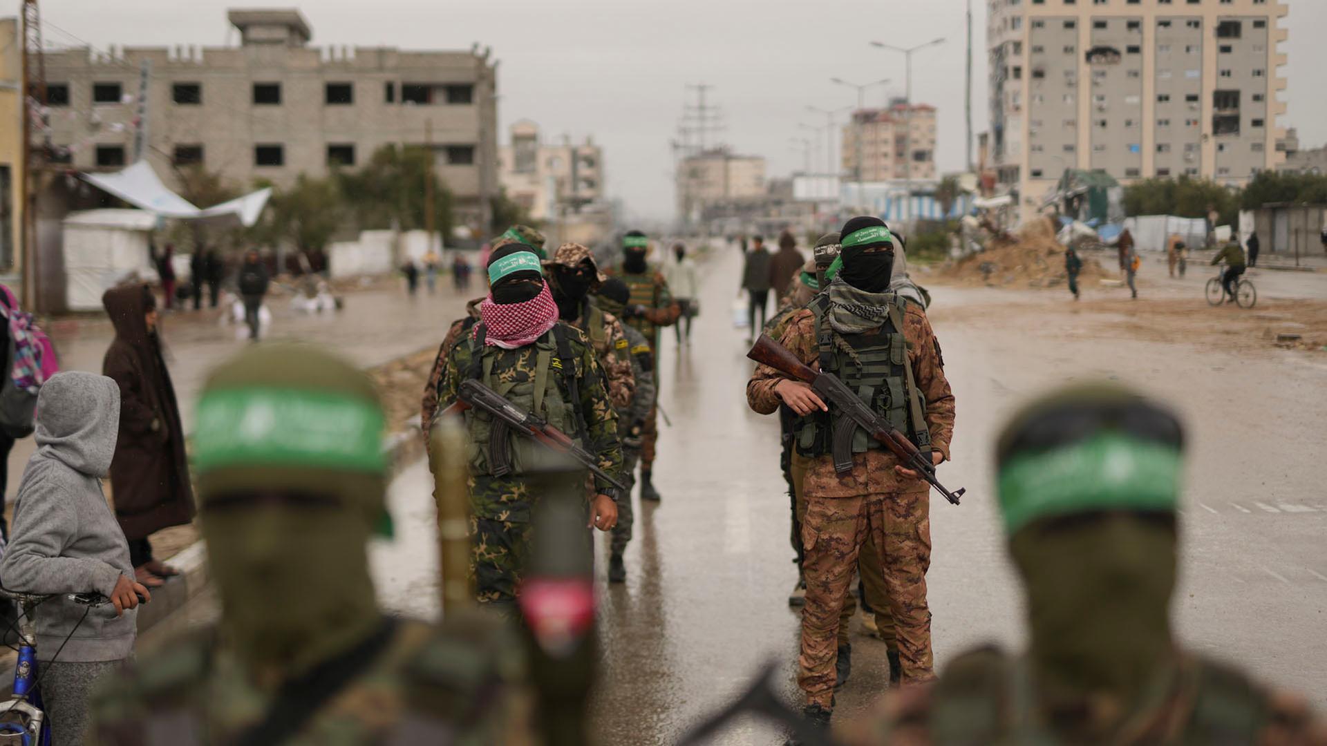 Vermummte und bewaffnete Mitglieder der Terrororganisation Hamas gehen in Nuserait im Gazastreifen in Stellung. | dpa
