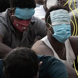 Menschen aus China, Vietnam und Äthiopien, die vermutlich Opfer von Menschenhandel wurden und zur Arbeit in betrügerischen Zentren gezwungen wurden, sitzen mit maskierten Gesichtern auf dem Boden.