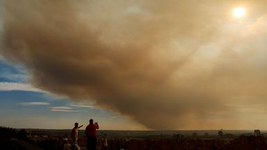Von einem Park in Madrid aus schauen Menschen auf die Rauchschwaden des Waldbrands