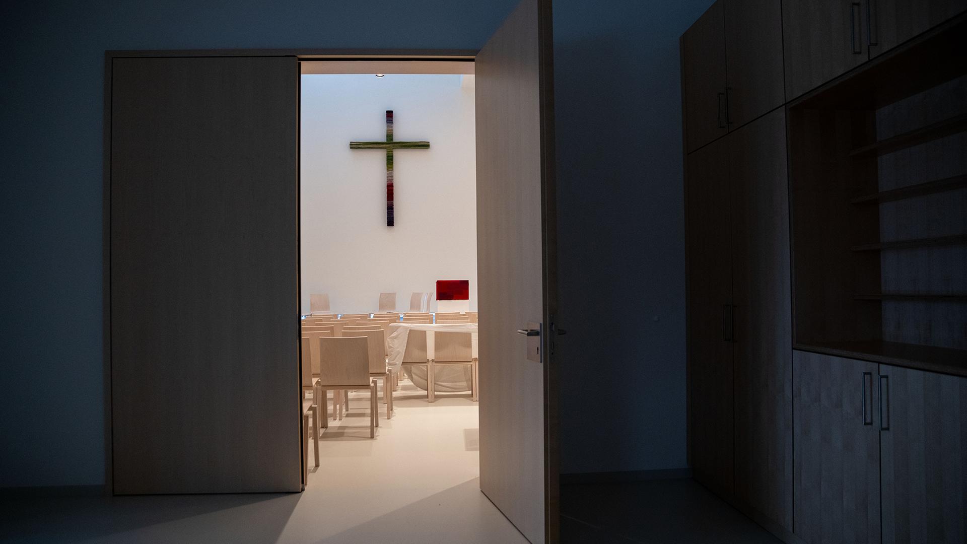 Ein Kreuz hängt im Innenraum einer Kirche an der Wand. | dpa