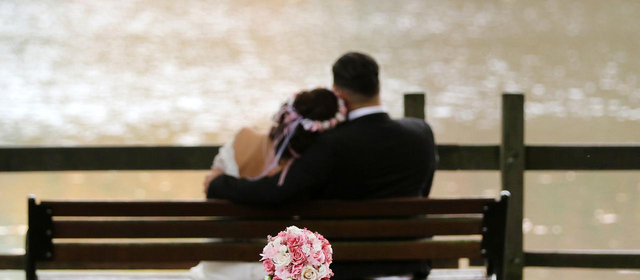 Ein Hochzeitspaar sitzt auf einer Bank