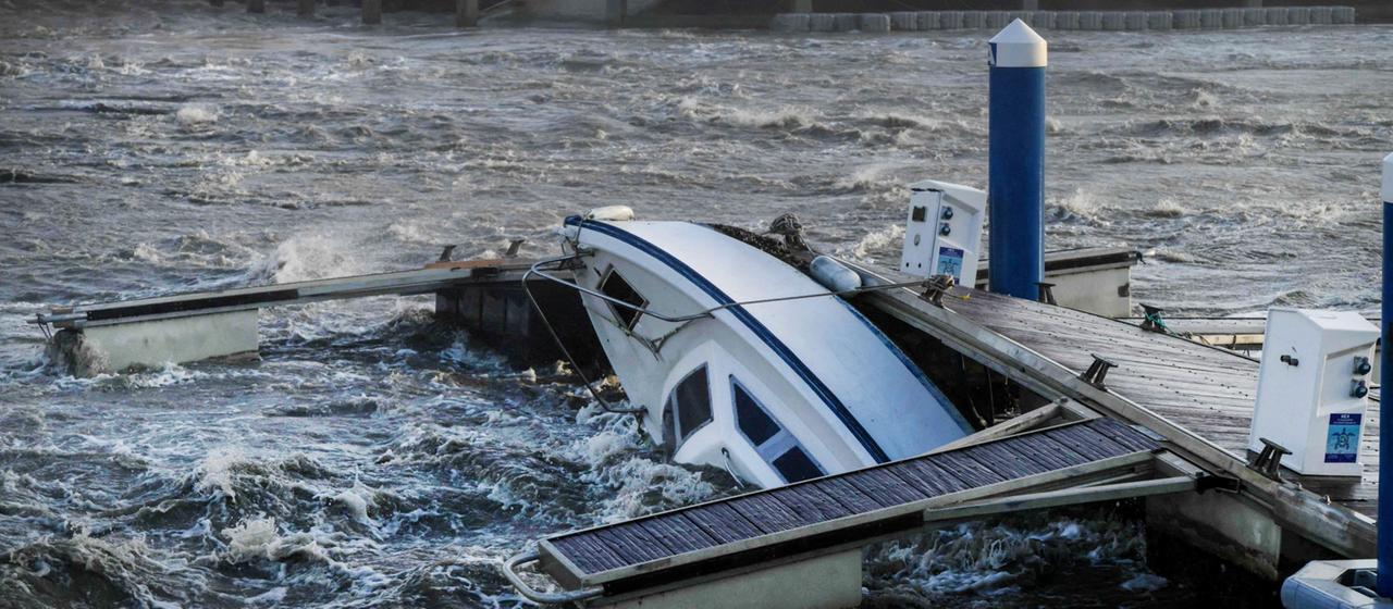 Ein Boot wird durch schnell fließendes Wasser und Wind zum Teil unter Wasser gedrückt.