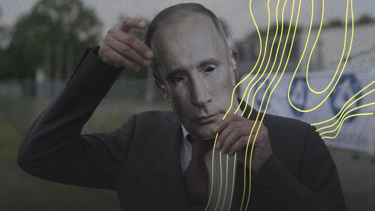 Ein Mann setzt eine Putin-Maske auf.