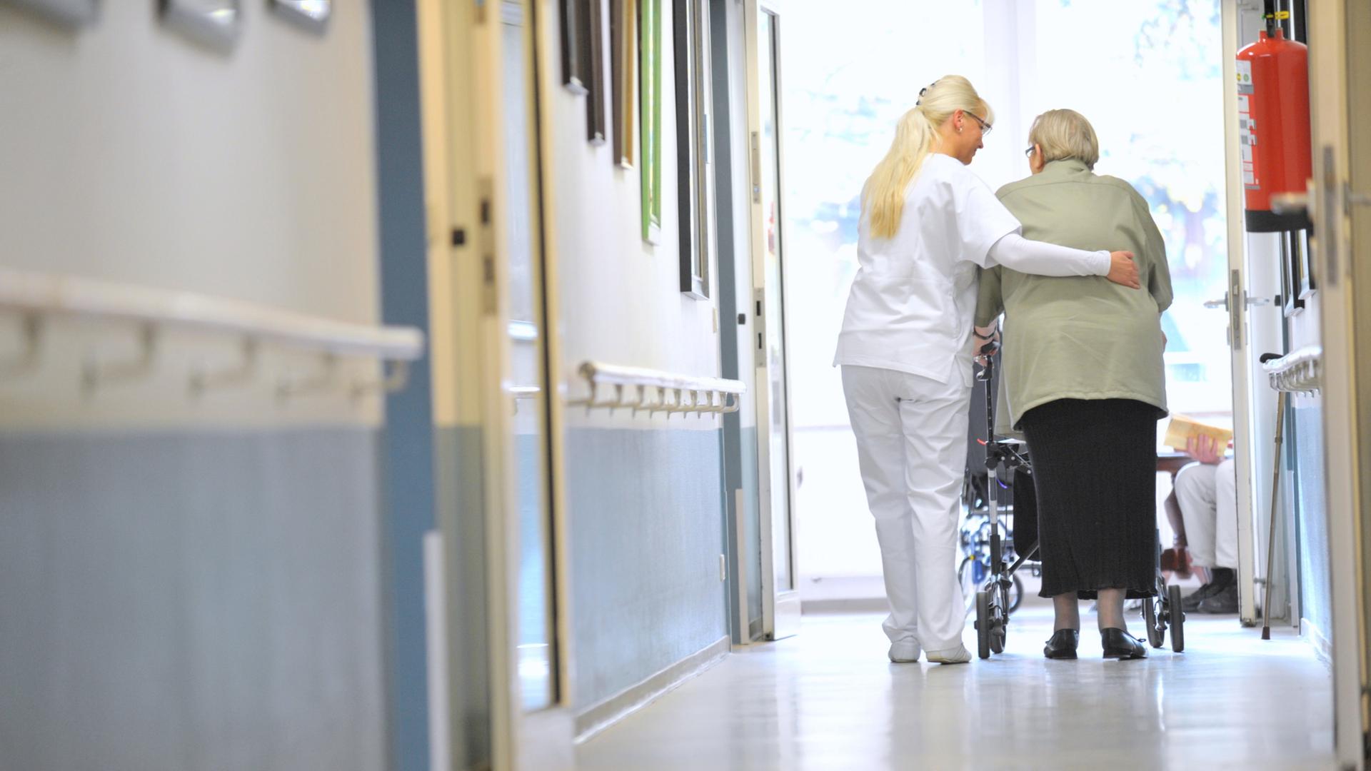 Eine Pflegekraft geht mit einer Seniorin über den Flur eines Pflegeheims. | ARD-aktuell / Kruse