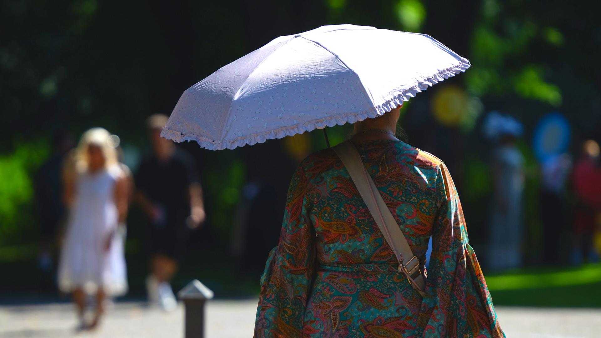 Eine Frau sch�tzt sich mit einem Regenschirm vor der Sonne.  | Florian Wiegand/dpa