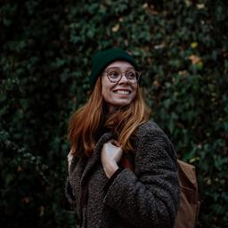 Eine lächelnde Frau geht durch einen Park.