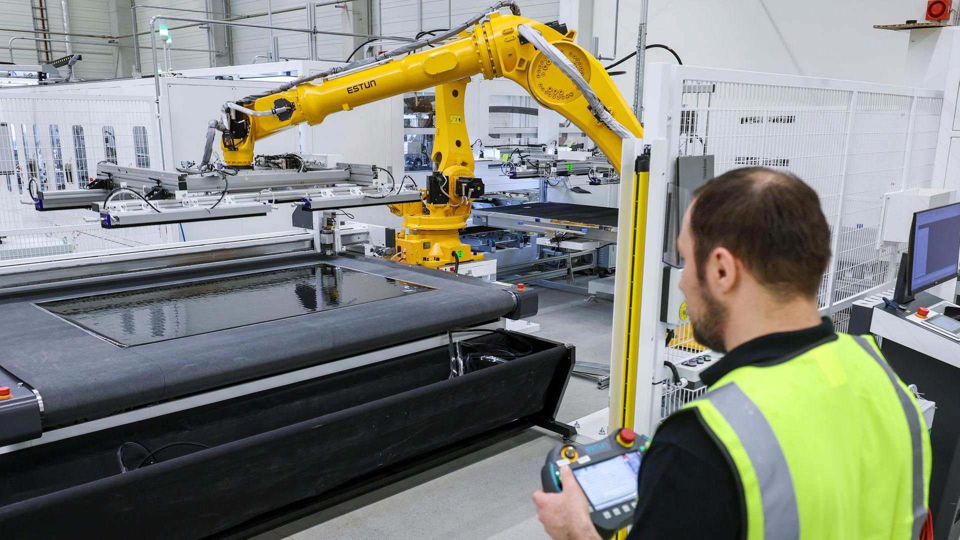 Ein Mitarbeiter Ã¼berwacht den Zuschnitt von Solarmodulen | picture alliance/dpa