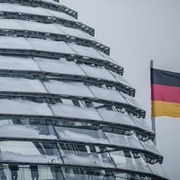 Blick auf die verschneite Kuppel des Reichstagsgebäudes mit einigen Besuchern und deutscher Flagge
