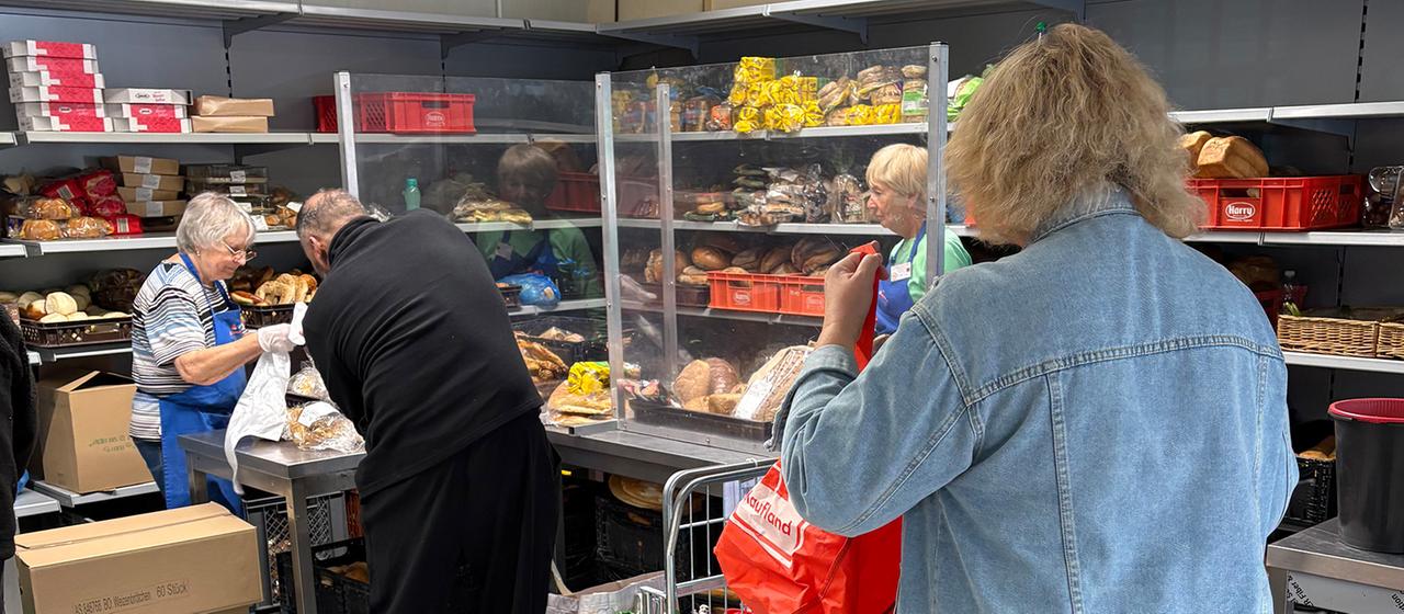 Mehrere Menschen stehen in einer Ausgabestelle der Tafel Ludwigshafen in einer Schlange.