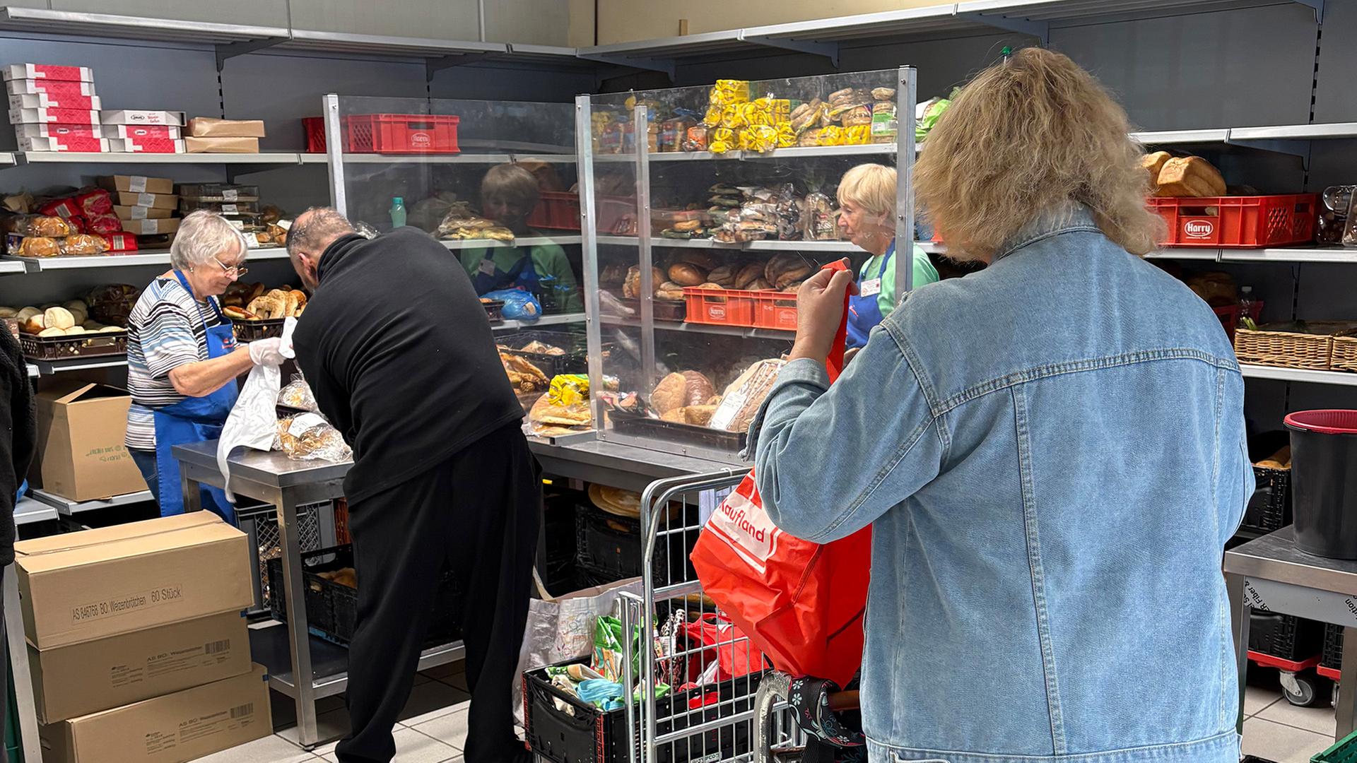 Mehrere Menschen stehen in einer Ausgabestelle der Tafel Ludwigshafen in einer Schlange. | SWR Mainz / Axel John 